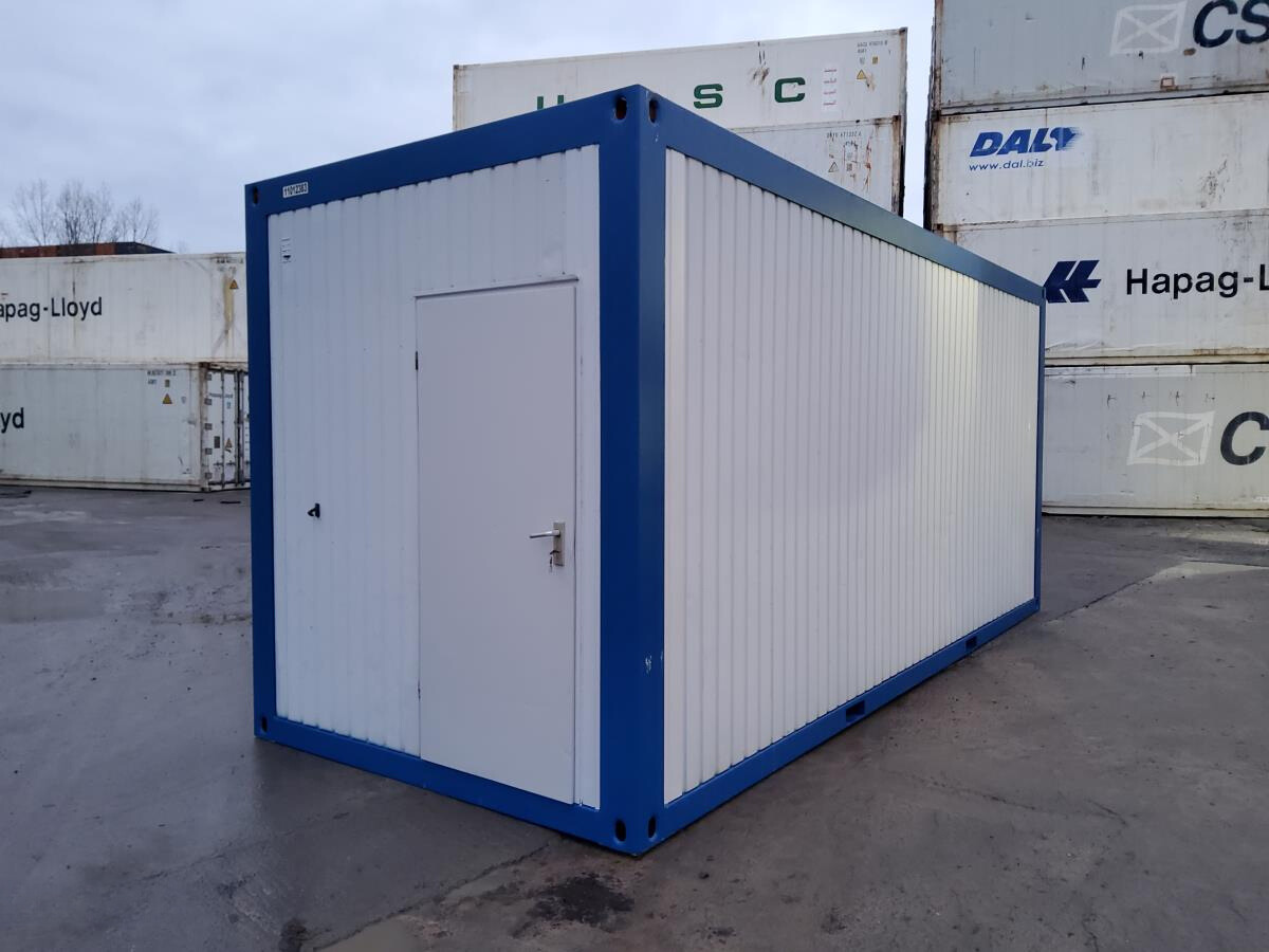 Contenedor oficina modular prefabricado de 20 pies, fabricado en acero color blanco y azul, utilizado como oficina portátil o espacio técnico, instalado en un patio industrial con contenedores marítimos al fondo.