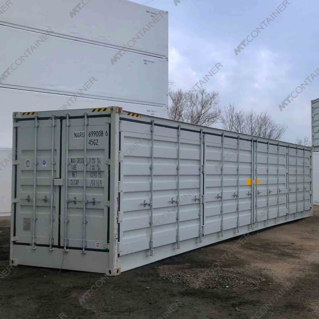 Contenedor marítimo Open Side de 40 pies color gris claro, fabricado en acero resistente, con puertas laterales abatibles a lo largo del costado para acceso total a la carga, ideal para carga y descarga de mercancías voluminosas, almacenamiento industrial y uso logístico, ubicado en un patio exterior.